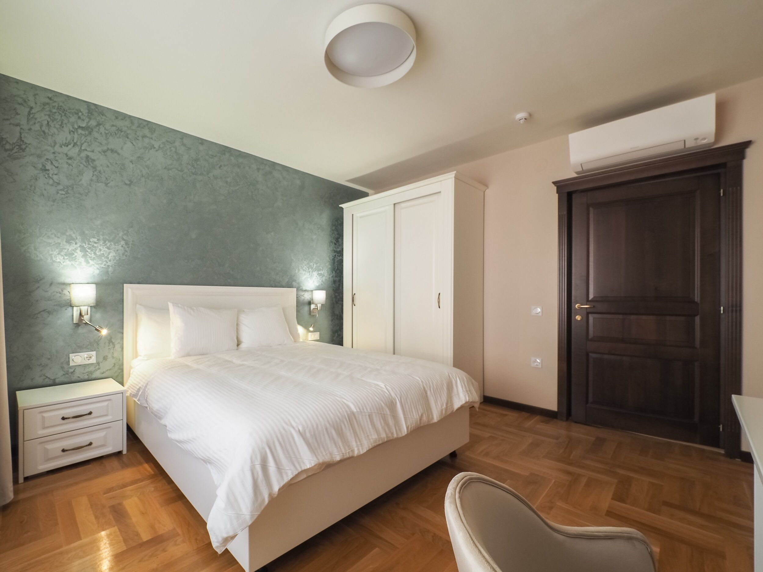 A bedroom with a bed, bedside tables, a wardrobe, and a chair.