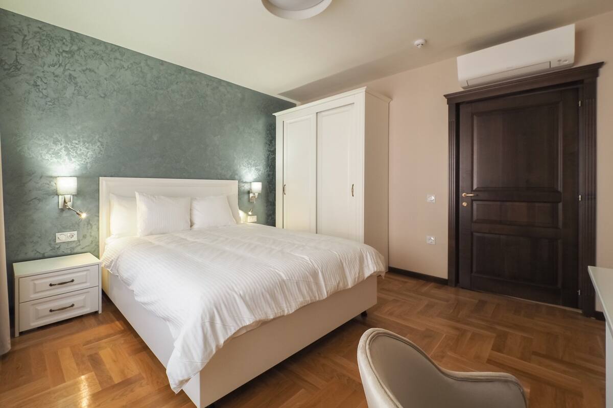 A bedroom with a bed, bedside tables, a wardrobe, and a chair.