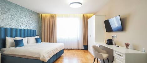 A hotel room with a bed, a desk, a chair, a television, and a window with curtains.