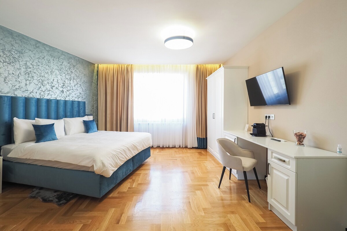A hotel room with a bed, a desk, a chair, a television, and a window with curtains.