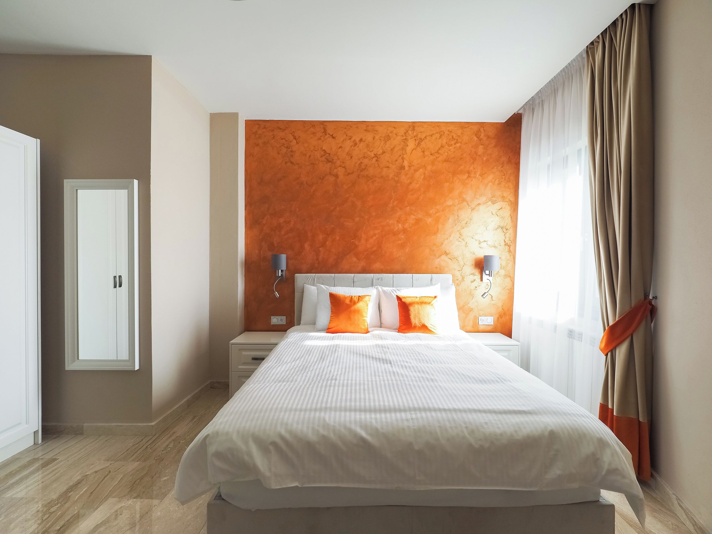 A modern hotel room with a large bed, two bedside tables, and a wall-mounted light fixture.