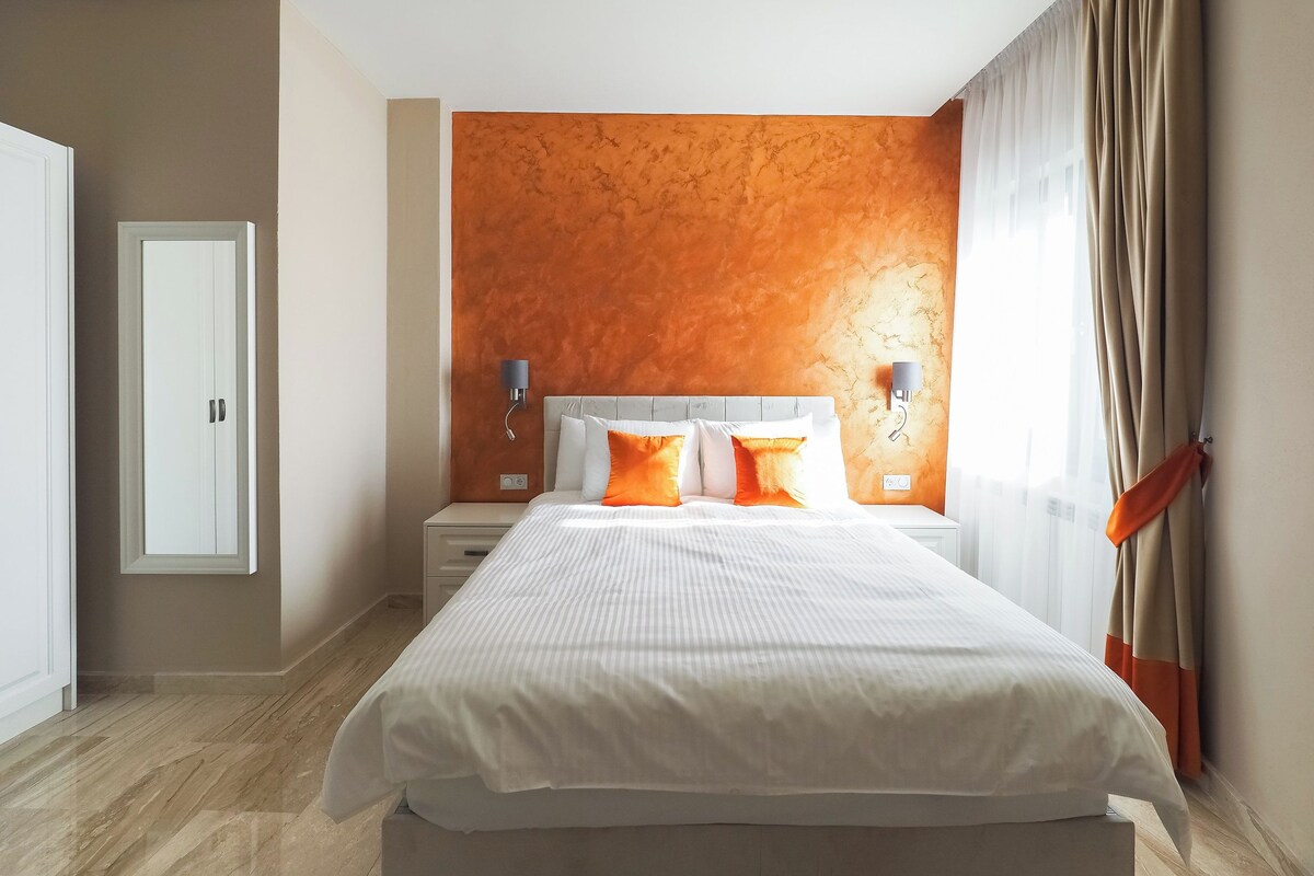 Une chambre d’hôtel moderne avec un grand lit, deux tables de chevet et un luminaire fixé au mur.