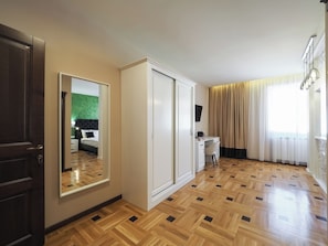 A hotel room with a wooden parquet floor, a bed with a green headboard, a desk with a chair, a wardrobe, and a large mirror. - Boutique Central Sibiu (Sibiu)