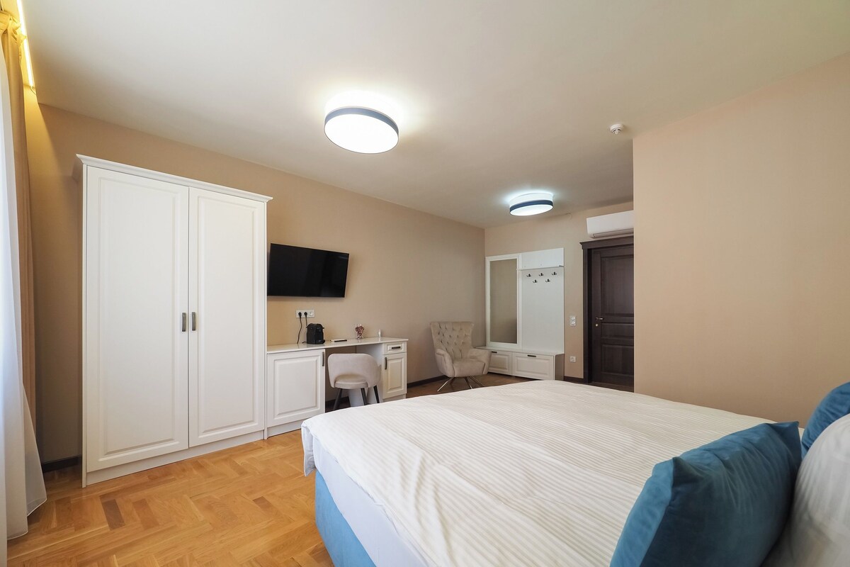 Une chambre à coucher avec un grand lit, un bureau, une chaise, une armoire, une télévision et un miroir.