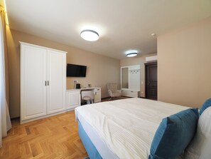Une chambre à coucher avec un grand lit, un bureau, une chaise, une armoire, une télévision et un miroir.