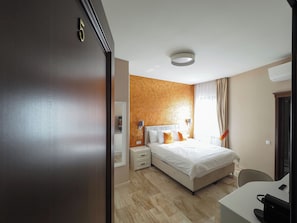 Una habitación de hotel con una cama, mesitas de noche, un escritorio y una silla.