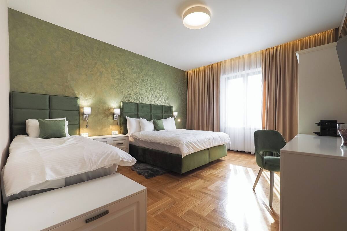 A hotel room with two beds, a desk, and a chair.