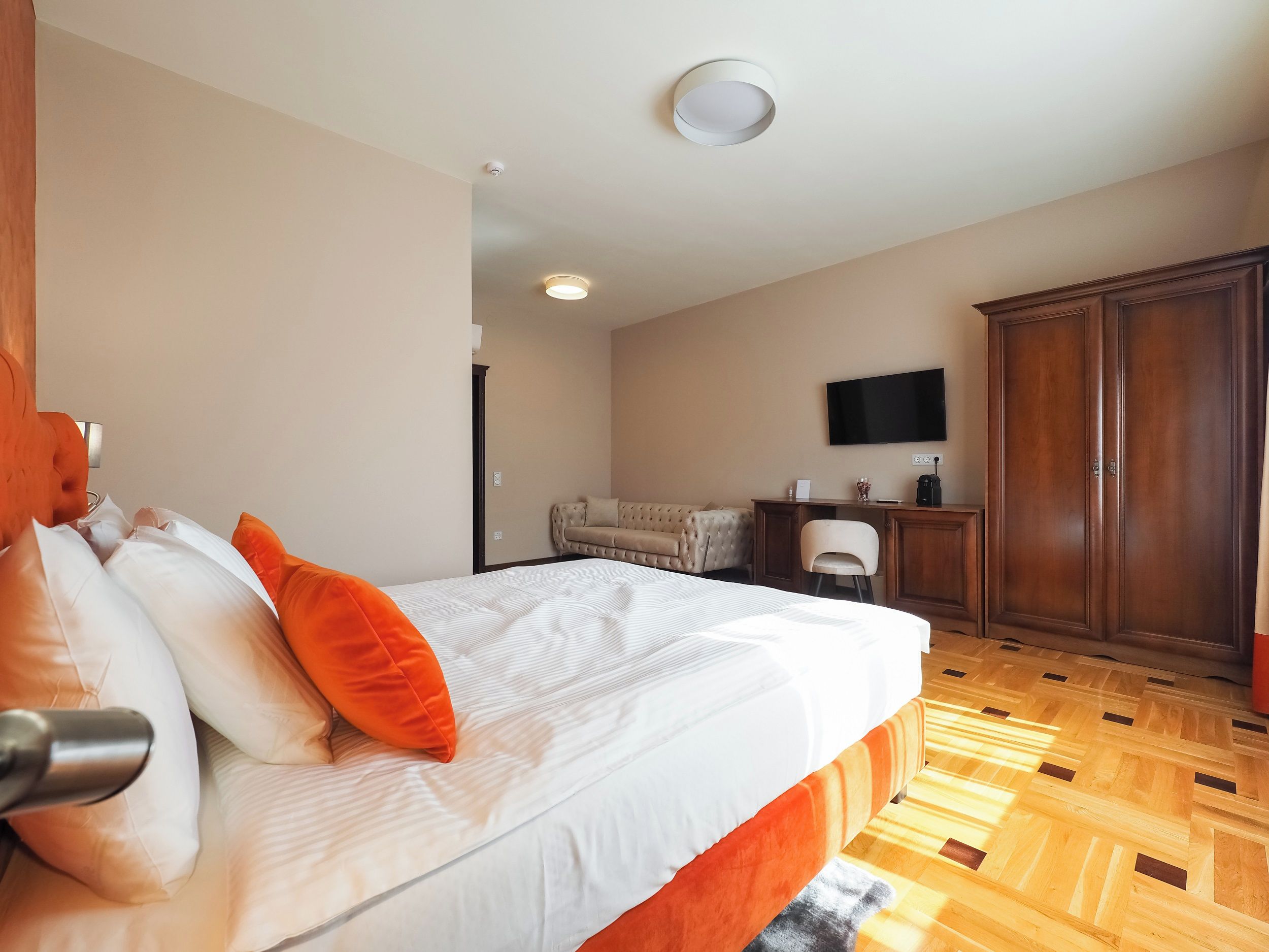 Una habitación de hotel con una cama, un escritorio, un televisor y un armario.