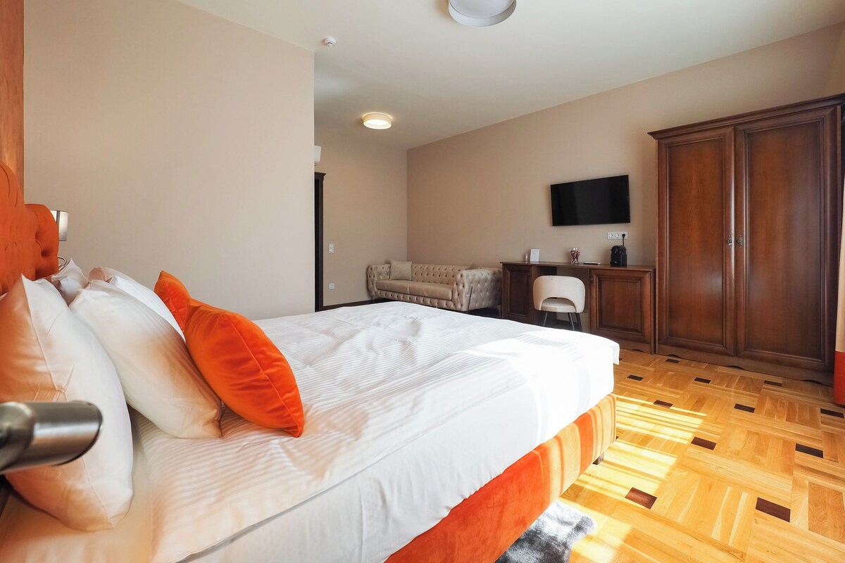 A hotel room with a bed, a desk, a television, and a wardrobe.