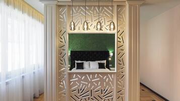 A bedroom with a green wall, a black headboard, and a decorative partition with light fixtures.