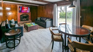 A living room with a fireplace, a sofa, a coffee table, and a dining area with chairs and a glass table. - Comfy, Spacious & Convinient 3/2 house in Overland Park (Overland Park)