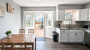 A modern kitchen with white cabinets, a wooden dining table, and a view to the outside. - Comfy, Spacious & Convinient 3/2 house in Overland Park (Overland Park)