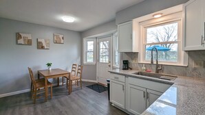 A kitchen with a granite countertop, white cabinets, a dining table with chairs, and a coffee maker. - Comfy, Spacious & Convinient 3/2 house in Overland Park (Overland Park)