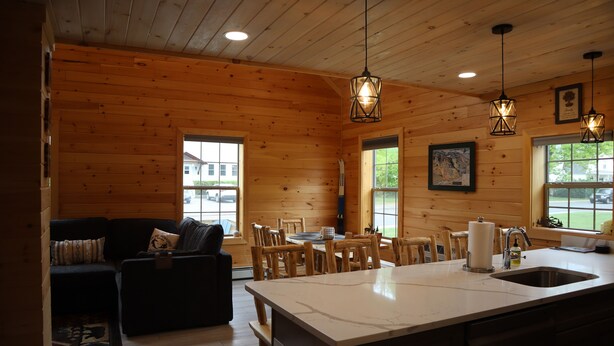 A wooden cabin interior with a dining area, kitchen, and living space. - Newly Built Home: Perfectly Located Near Loon Mountain & Downtown Lincoln, NH! (Lincoln)
