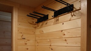 A wooden room with a sloped ceiling, a door, and a black bench. - Newly Built Home: Perfectly Located Near Loon Mountain & Downtown Lincoln, NH! (Lincoln)