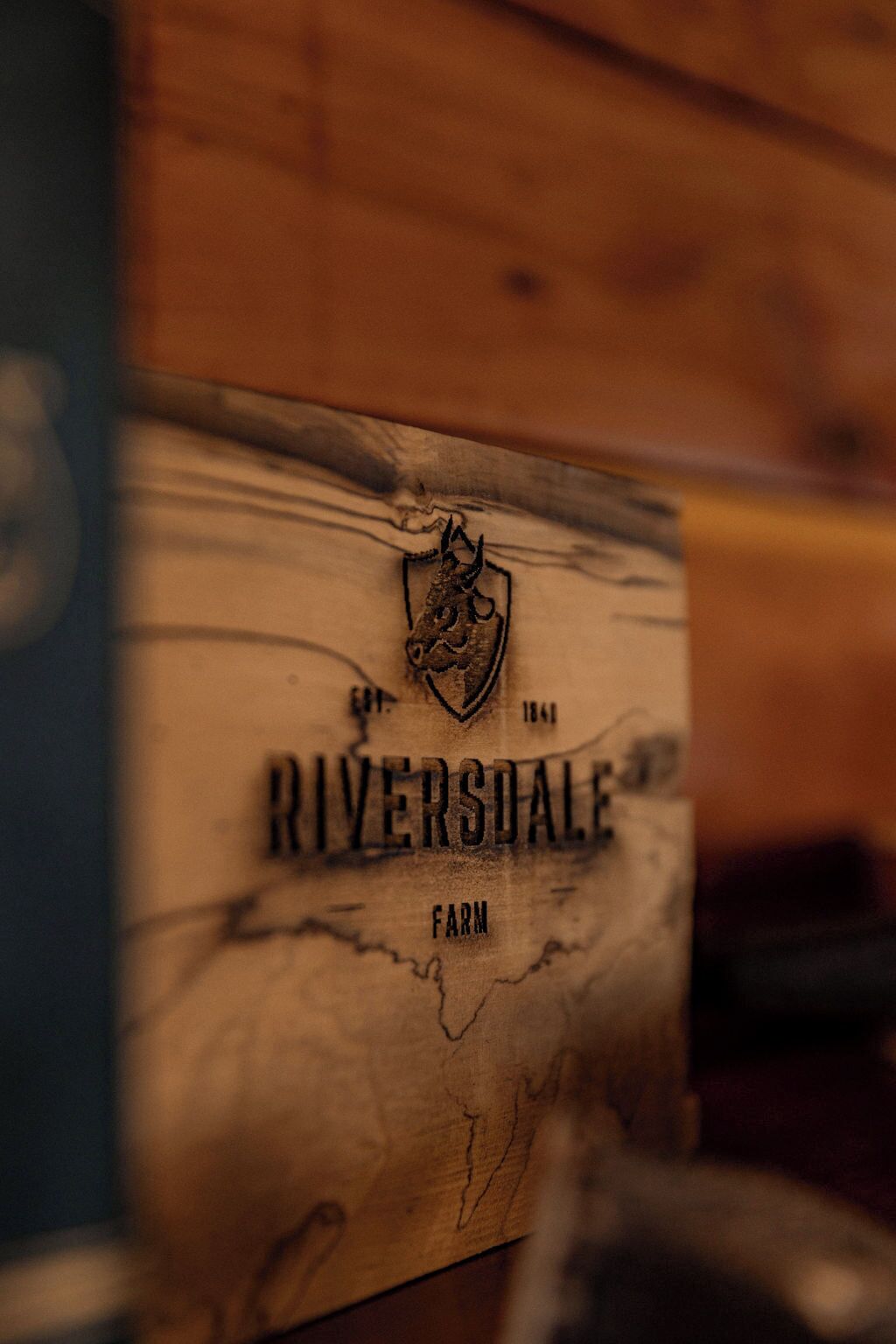 Un panneau en bois portant l’inscription « RIVERSDALE FARM » et orné d’un écusson.