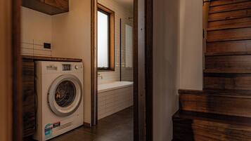 A laundry area with a washing machine, a sink, and a window.