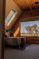 Habitación con un amplio ventanal que ofrece vista a árboles y cielo despejado.