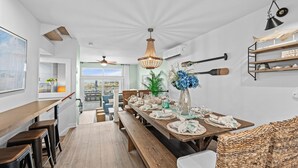 Ein Essbereich mit einem langen Holztisch, gedeckt für eine Mahlzeit, Bänken und einer Pendelleuchte.