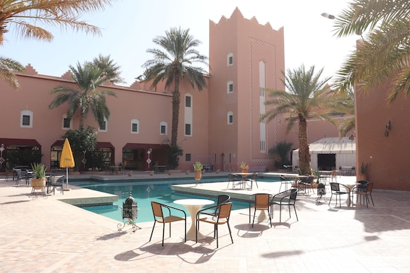A poolside area with outdoor seating and palm trees.