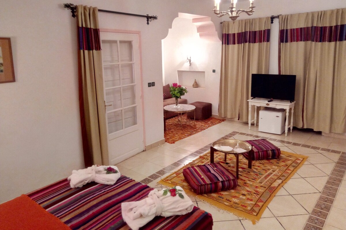 A hotel room with a bed, a TV, a small table, and a sofa.