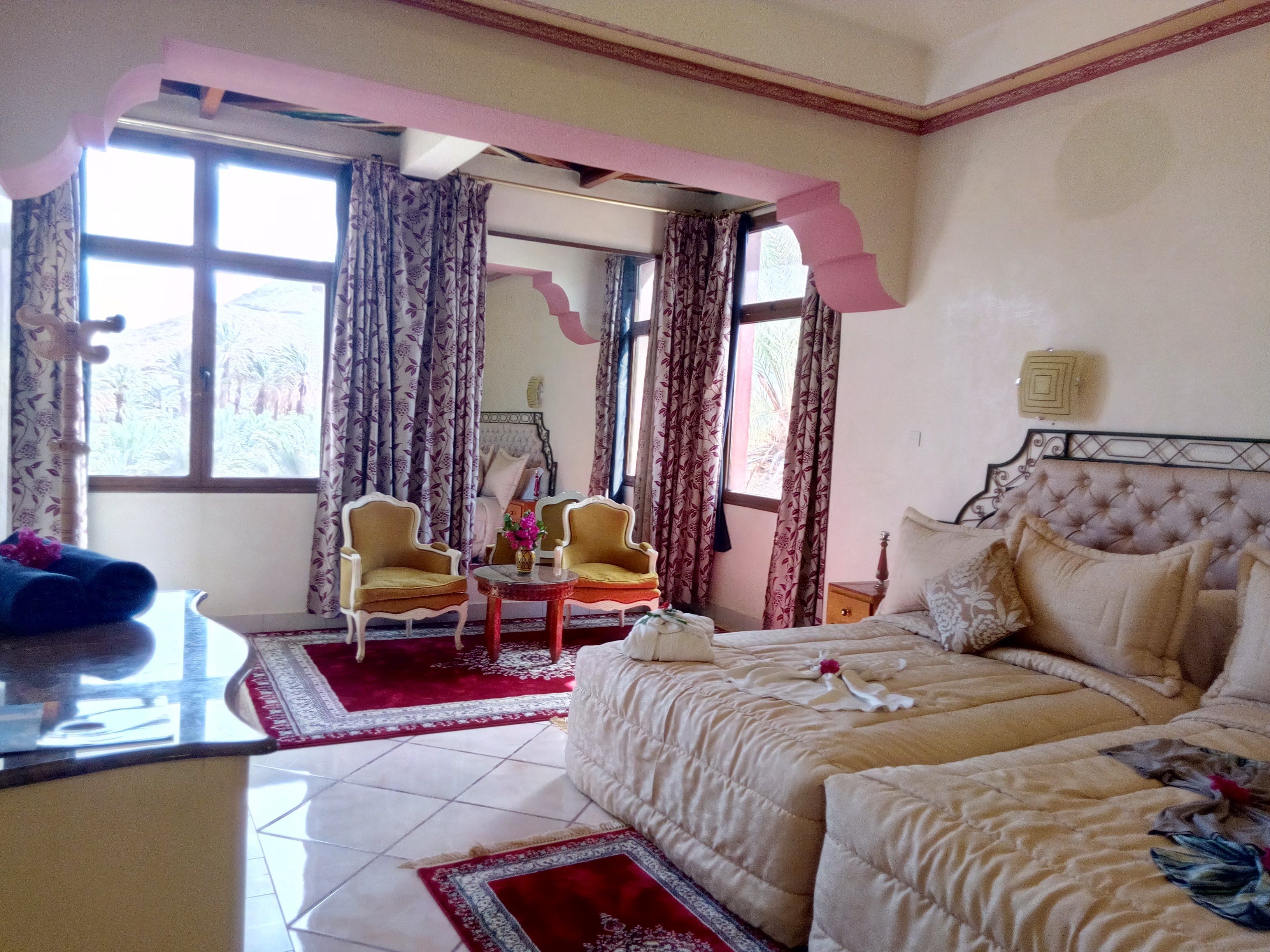 A hotel room with a bed, two armchairs, a small table, and a window with curtains.