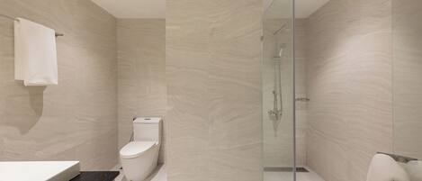 Un baño moderno con cabina de ducha de vidrio, un inodoro y un lavabo con encimera negra.