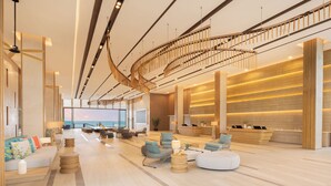 A spacious lobby with a curved staircase, comfortable seating areas, a reception desk, and a large window offering a view of the ocean. - Eastin Resort Rayong (Ban Chang)