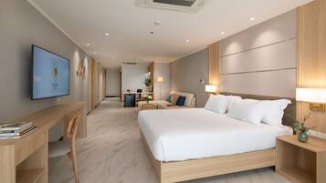 A modern hotel room with a large bed, a desk, and a television on the wall.