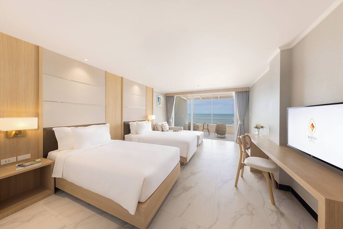A hotel room with two beds, a desk, and a TV.