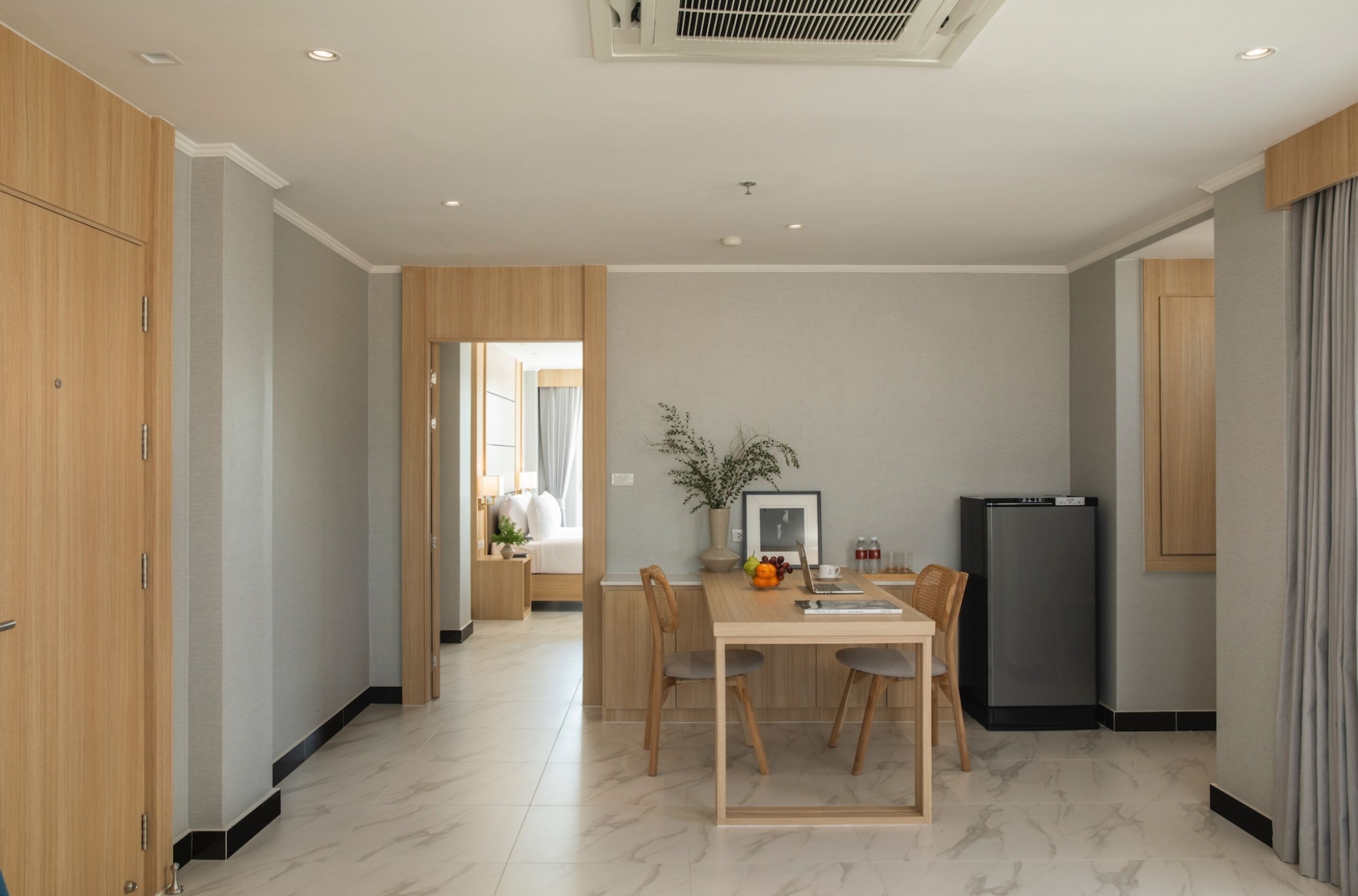 Una cocina moderna con una mesa de comedor, sillas, un refrigerador y una planta.