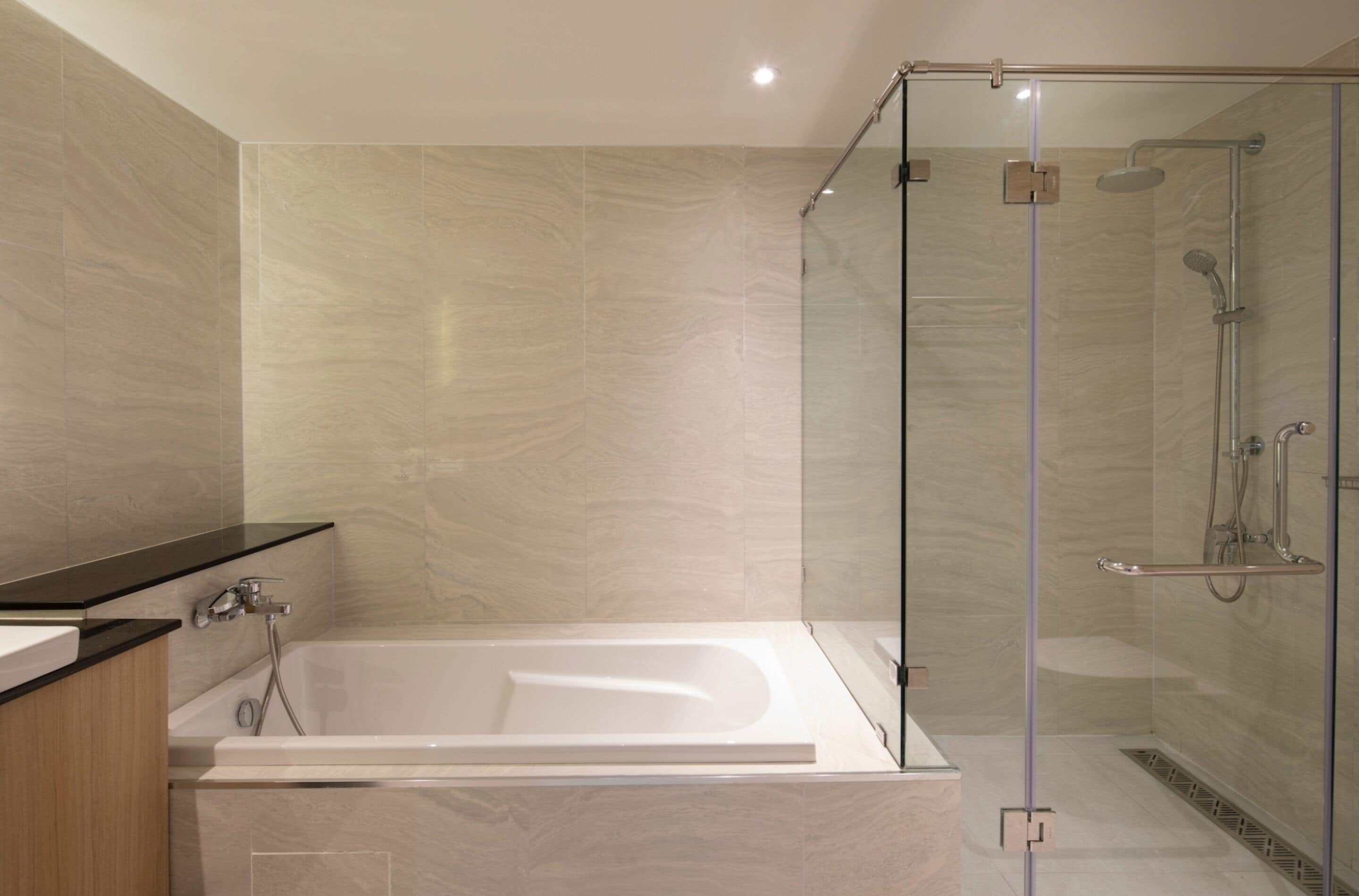 A modern bathroom with a glass-enclosed shower, a freestanding bathtub, and a vanity with a dark countertop.