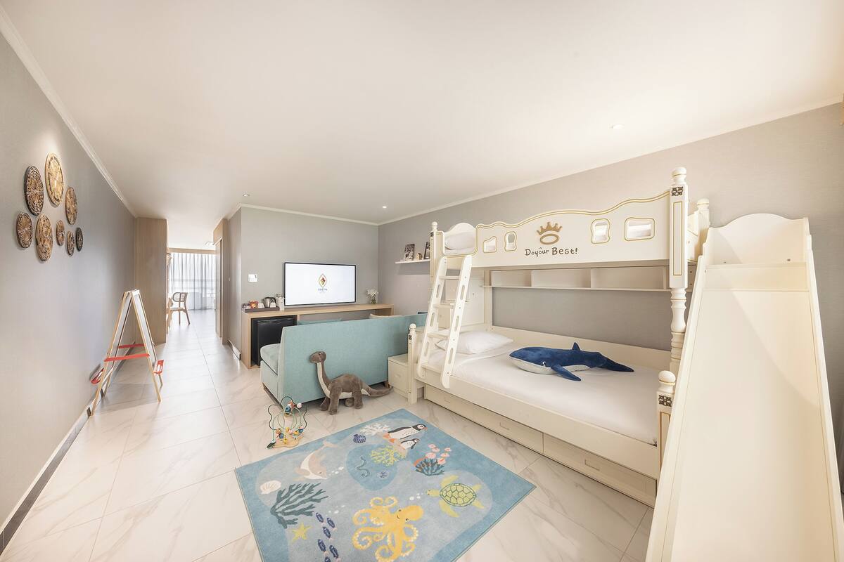 A children's room with bunk beds, a desk, and a play area.