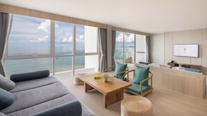A modern living room with a large window overlooking the sea, a wooden coffee table, and a sofa. - Eastin Resort Rayong (Ban Chang)