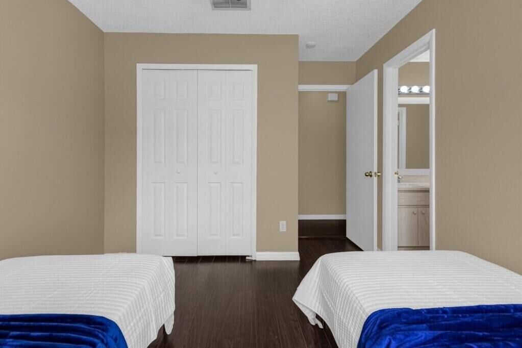 Une chambre avec deux lits, une armoire et une salle de bain visible à travers une porte ouverte.