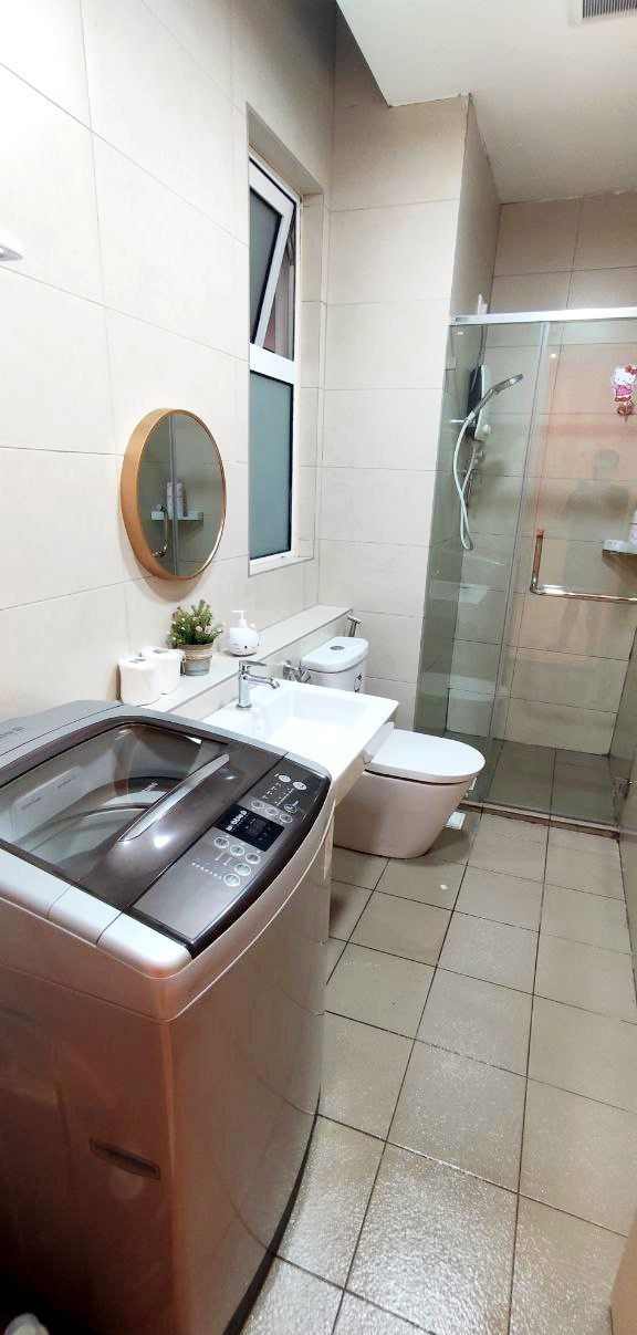 A modern bathroom with a washing machine, toilet, and glass shower enclosure.