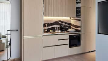A modern kitchen with light wood cabinetry, a marble backsplash, and built-in appliances.