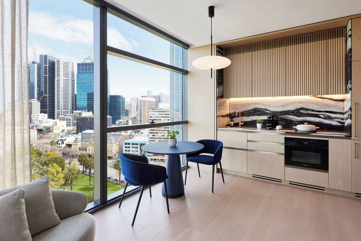 Eine moderne Küche mit Stadtblick, ausgestattet mit einem runden Tisch, zwei Stühlen und einem Einbauofen.