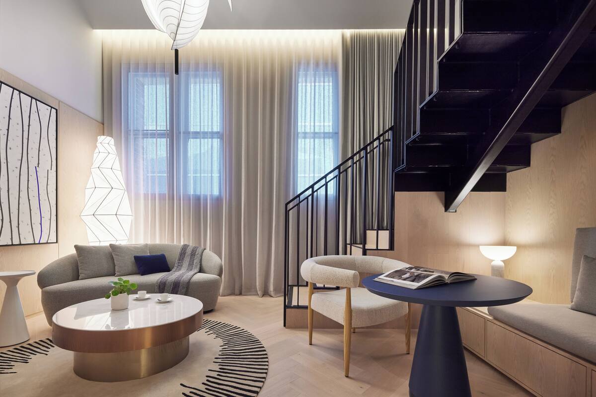 Ein modernes Wohnzimmer mit Treppe, Sofa, Couchtisch und Lesesessel.