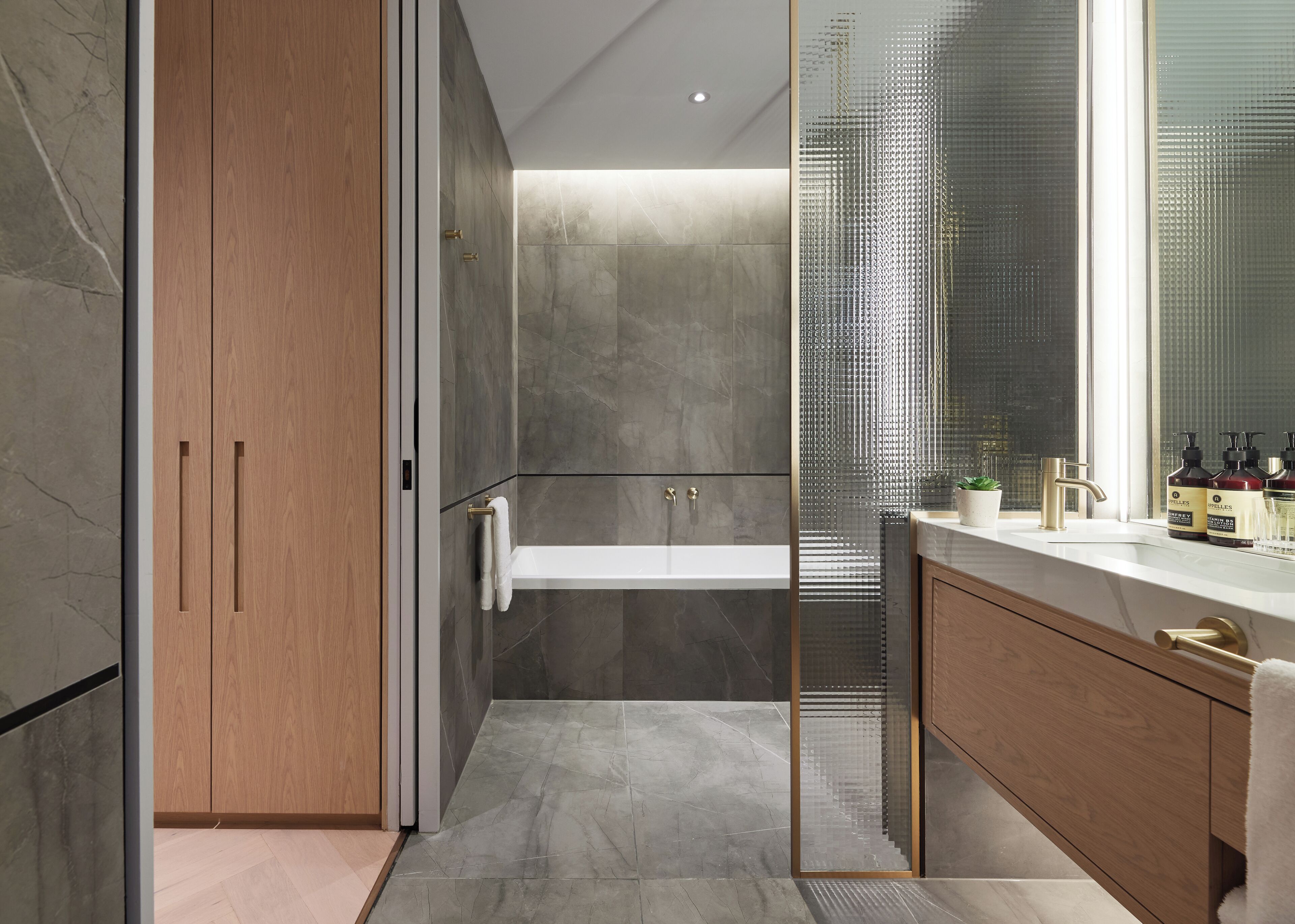 A modern bathroom with a glass-enclosed shower, a wooden vanity with a white countertop, and a large mirror.