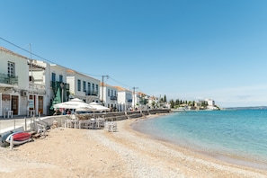 A coastal area with buildings, a beach, and a clear sky.
