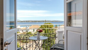 Un balcón abierto con vista al mar, una mesa con un florero y una silla.