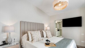 Una habitación de hotel moderna con una cama, mesitas de noche, un televisor de pantalla plana y una cafetera sobre una bandeja.
