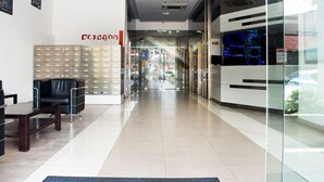A reception area with a glass partition, a reception desk, a black leather chair, and a wall-mounted nameplate. - Octagon Premium Ipoh Homestay (Ipoh)