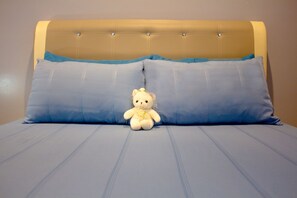 A bed with a headboard, two pillows, and a teddy bear.