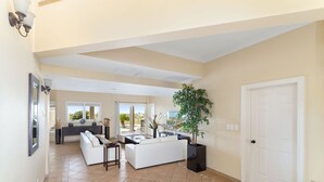 Un amplio salón con un conjunto de sofá blanco, una mesa de comedor y una planta grande en maceta.