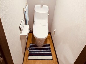 Une petite salle de bain avec des toilettes blanches, un plancher en bois et un tapis à rayures.