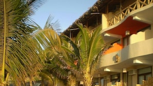 A resort with a pool area, lounge chairs, and a building with a thatched roof.