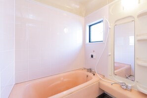 Bathroom features a bathtub and white tile walls.