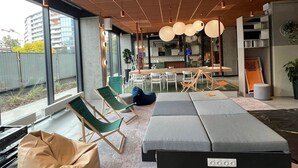 A modern interior with a large window, seating area, and a kitchen in the background. - Chillout Dorm Cracow (Kraków)